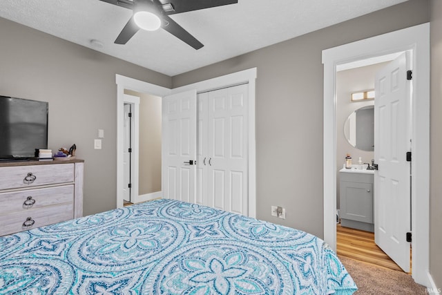 carpeted bedroom with ensuite bathroom, a textured ceiling, ceiling fan, sink, and a closet