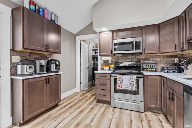 kitchen featuring tasteful backsplash, light wood-type flooring, stainless steel appliances, and dark brown cabinetry