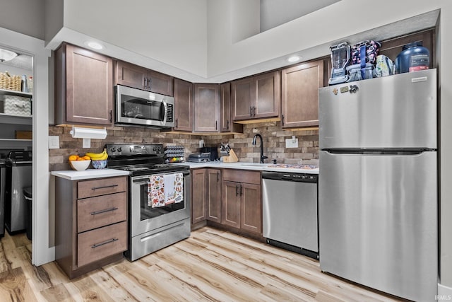 kitchen featuring stainless steel appliances, light hardwood / wood-style flooring, tasteful backsplash, and sink