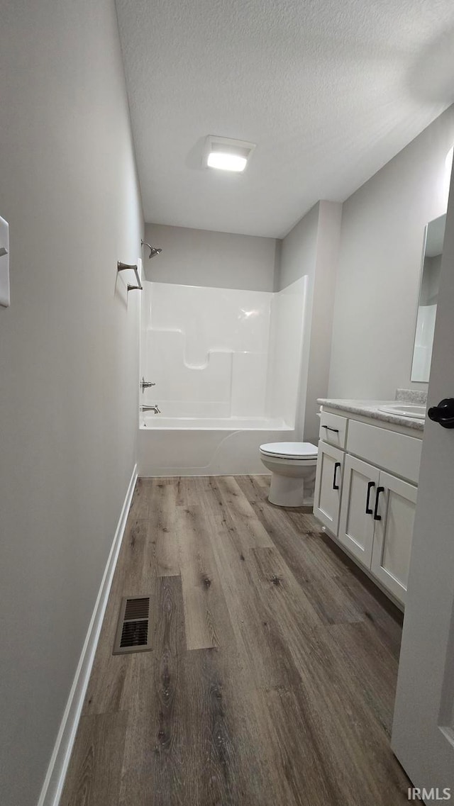 full bathroom featuring tub / shower combination, a textured ceiling, toilet, vanity, and hardwood / wood-style flooring