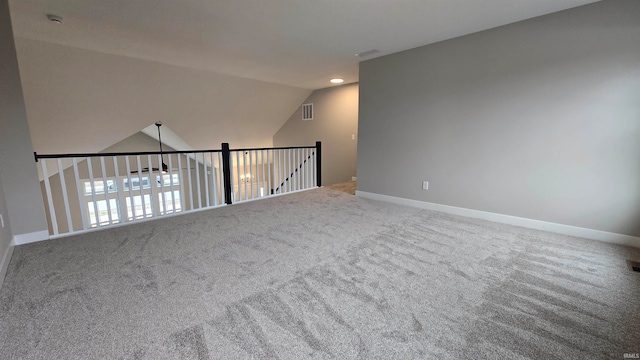 carpeted spare room featuring vaulted ceiling