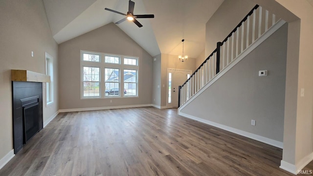 unfurnished living room with wood-type flooring, ceiling fan with notable chandelier, and high vaulted ceiling