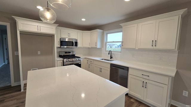 kitchen with backsplash, white cabinets, sink, appliances with stainless steel finishes, and decorative light fixtures