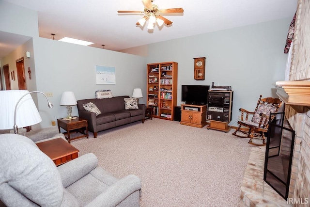 carpeted living room with ceiling fan and a fireplace