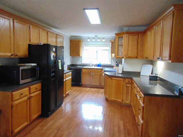 kitchen featuring sink, black appliances, a textured ceiling, and light wood-type flooring