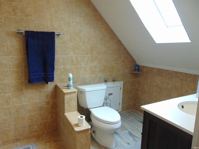 bathroom with vanity, tile walls, and vaulted ceiling with skylight