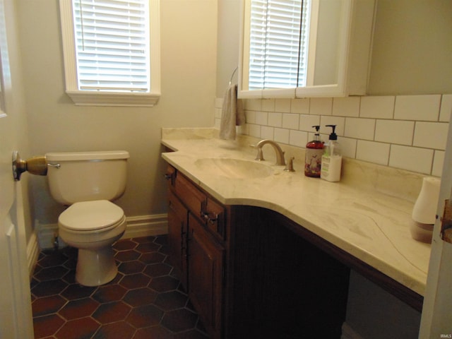 bathroom featuring backsplash, plenty of natural light, vanity, and toilet