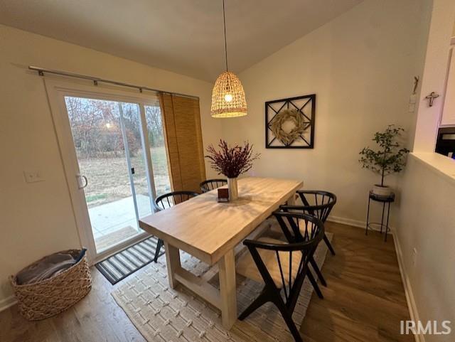 dining space featuring wood-type flooring and vaulted ceiling