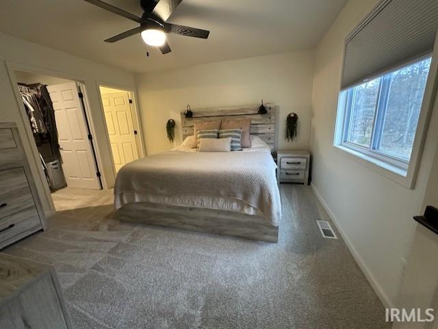 carpeted bedroom featuring a spacious closet and ceiling fan