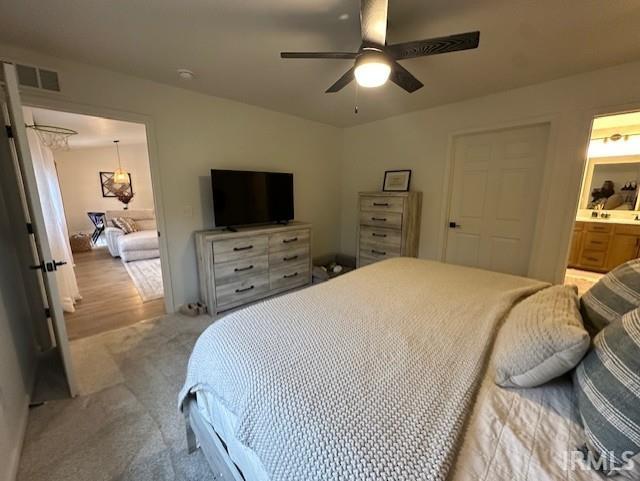 carpeted bedroom featuring ceiling fan and ensuite bathroom