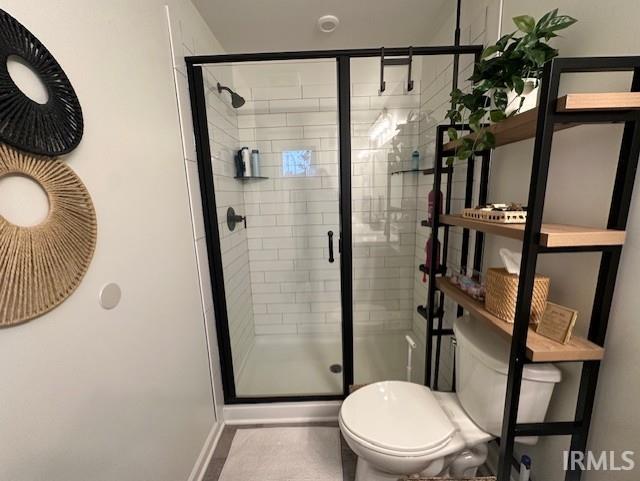 bathroom with toilet and a shower with shower door