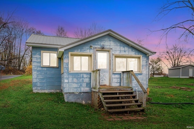 back house at dusk featuring a yard