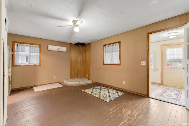 spare room featuring ceiling fan, hardwood / wood-style floors, wood walls, and a wall mounted air conditioner