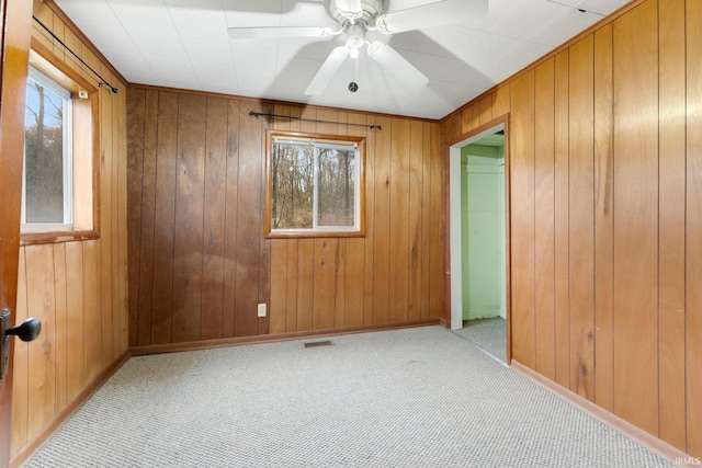 spare room with wooden walls, ceiling fan, and light colored carpet