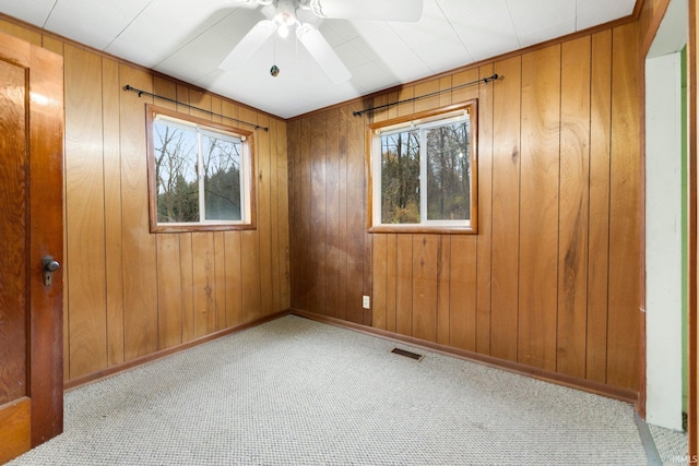 carpeted spare room with ceiling fan and wooden walls