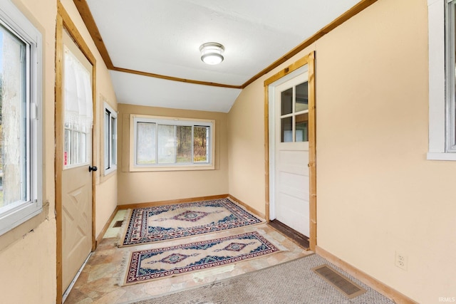 entryway featuring light colored carpet, lofted ceiling, and ornamental molding