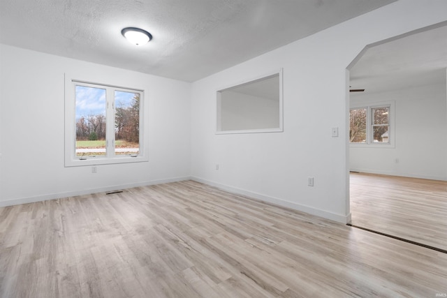 empty room with ceiling fan, a textured ceiling, and light hardwood / wood-style flooring