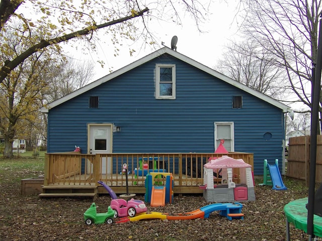 rear view of property with a trampoline and a wooden deck