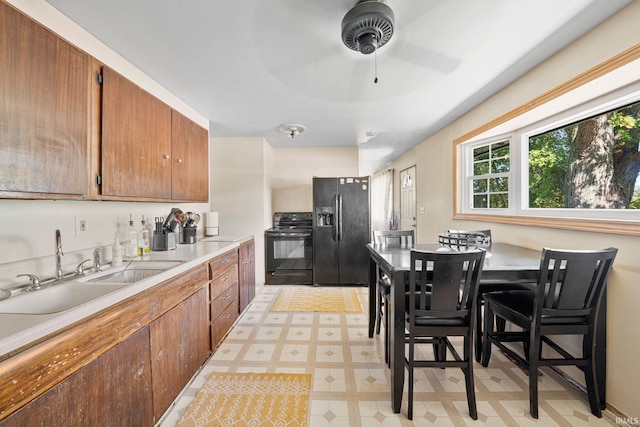 kitchen featuring sink, ceiling fan, a breakfast bar area, and black appliances