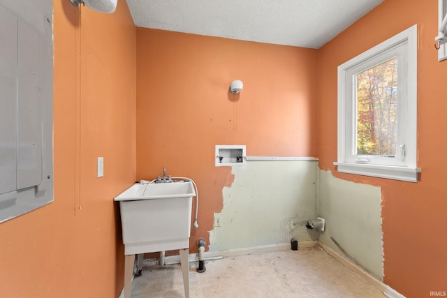 clothes washing area featuring hookup for a washing machine, a textured ceiling, electric panel, and sink