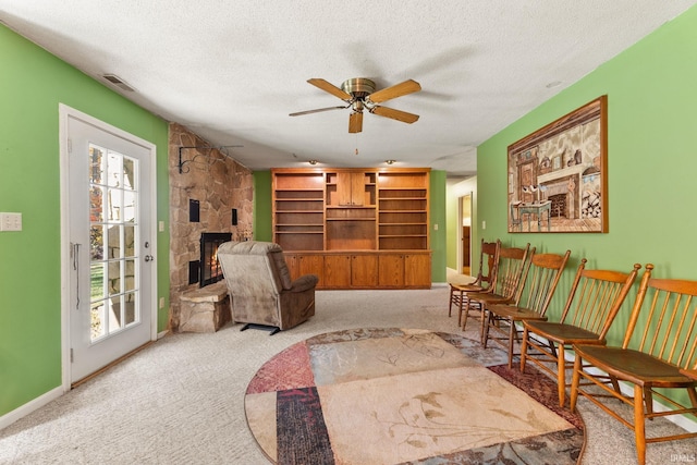 living area with plenty of natural light, light colored carpet, and a textured ceiling