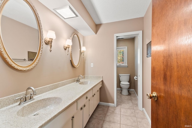 bathroom with tile patterned flooring, a textured ceiling, vanity, and toilet