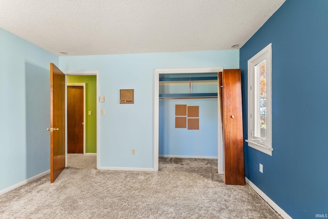 unfurnished bedroom featuring light carpet, a textured ceiling, and a closet