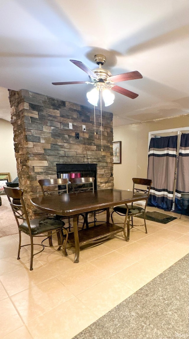 interior space featuring tile patterned floors, ceiling fan, and a stone fireplace