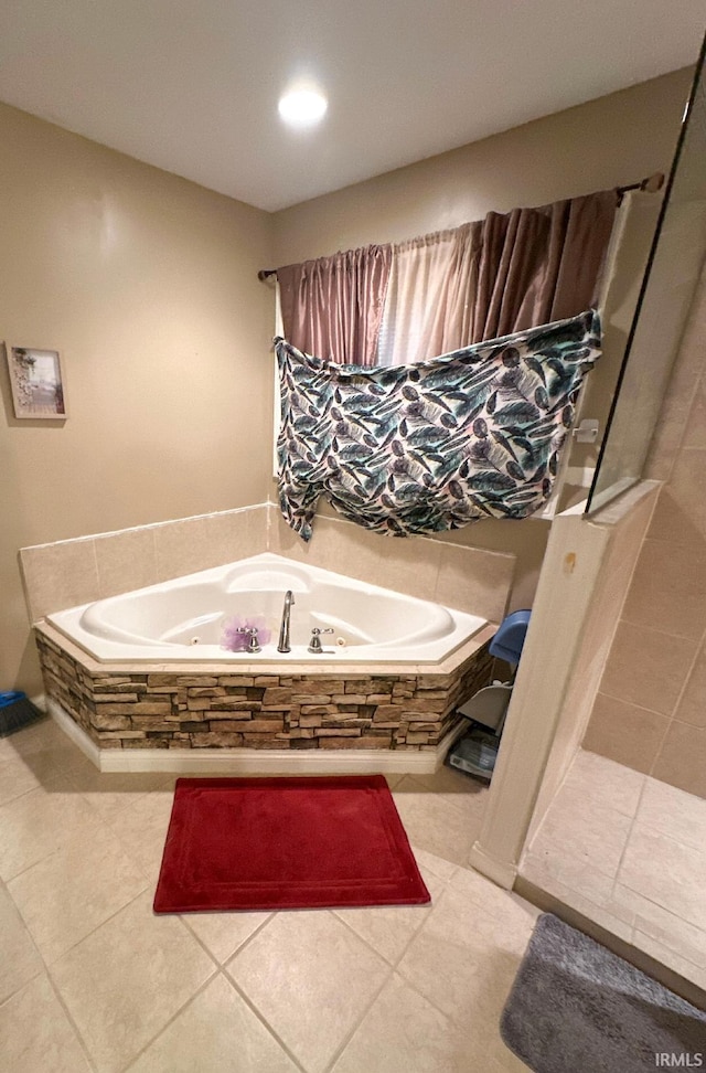 bathroom with tile patterned floors and a relaxing tiled tub