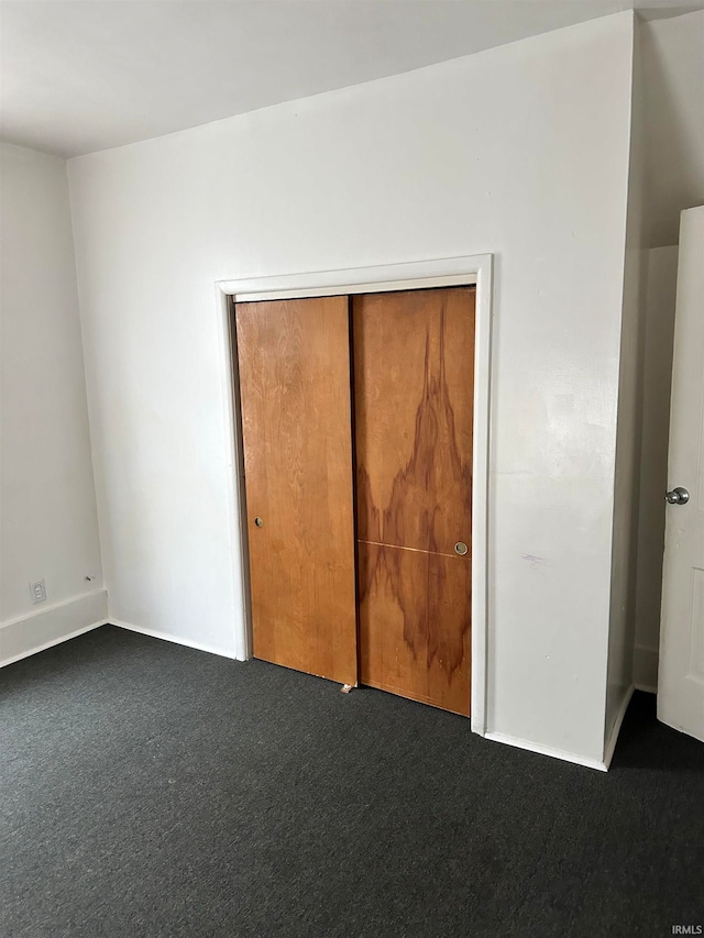 unfurnished bedroom featuring dark carpet and a closet