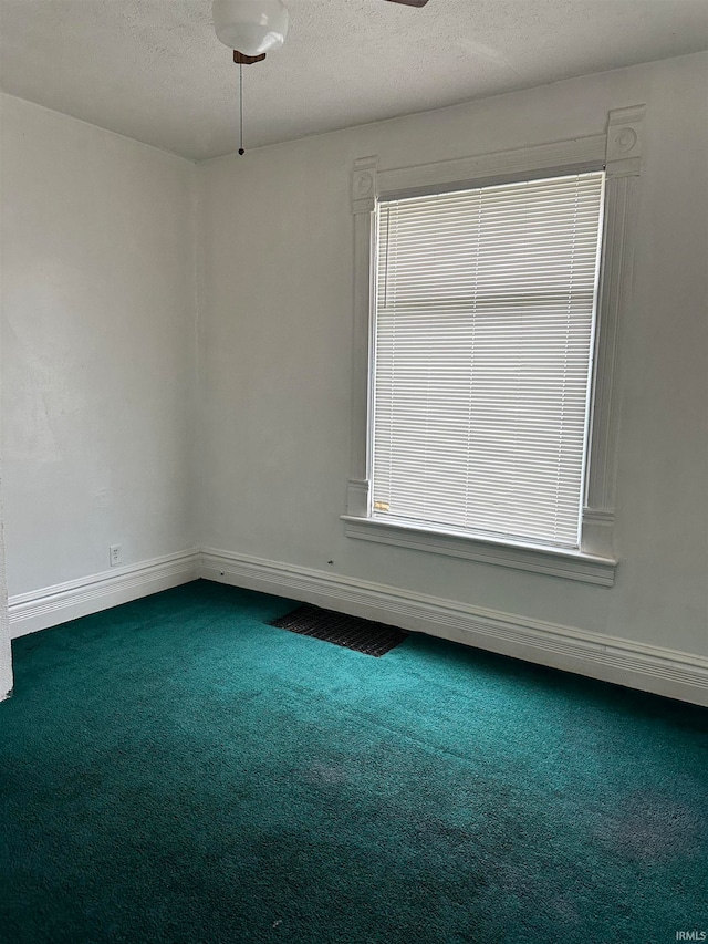 carpeted spare room featuring ceiling fan and a textured ceiling