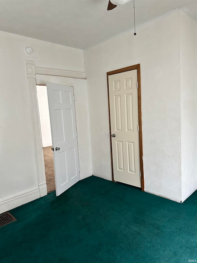 empty room featuring dark carpet and ceiling fan