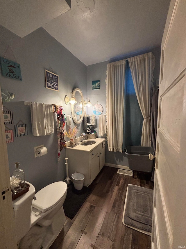 bathroom with vanity, toilet, wood finished floors, and visible vents