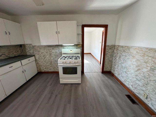 kitchen featuring white range with gas stovetop, white cabinets, and dark hardwood / wood-style floors