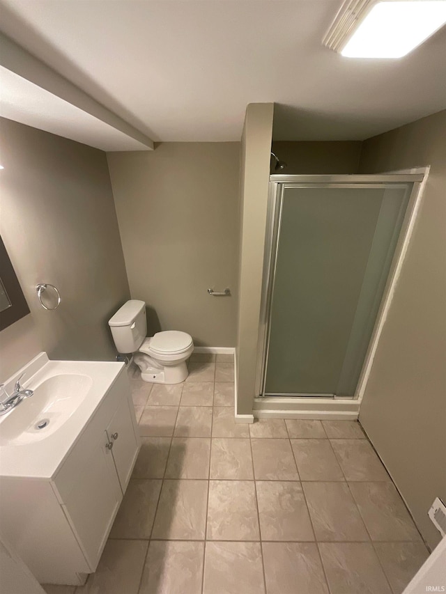 bathroom with tile patterned floors, vanity, a shower with shower door, and toilet