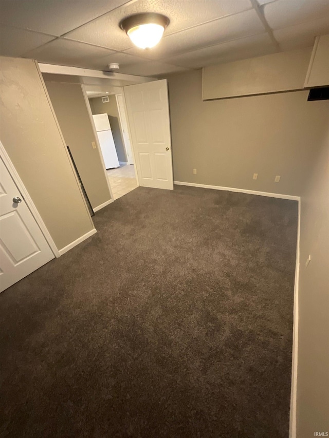 empty room featuring a paneled ceiling and dark carpet