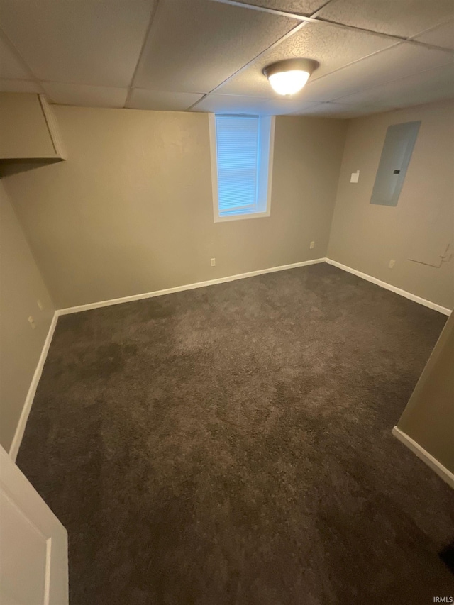 basement with electric panel, dark carpet, and a drop ceiling