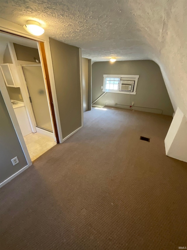 bonus room with carpet flooring, a wall mounted AC, and a textured ceiling