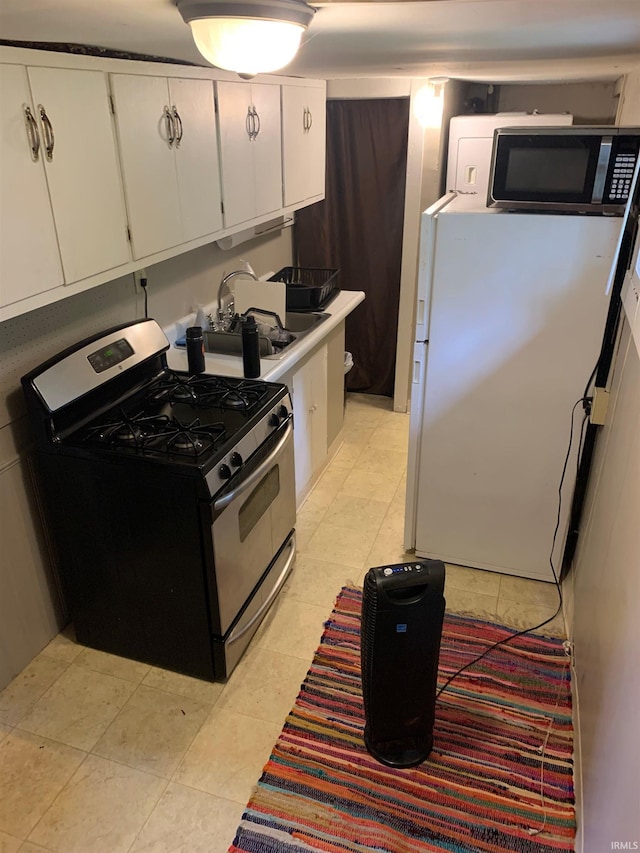 kitchen with light tile patterned flooring, sink, white cabinetry, and stainless steel appliances