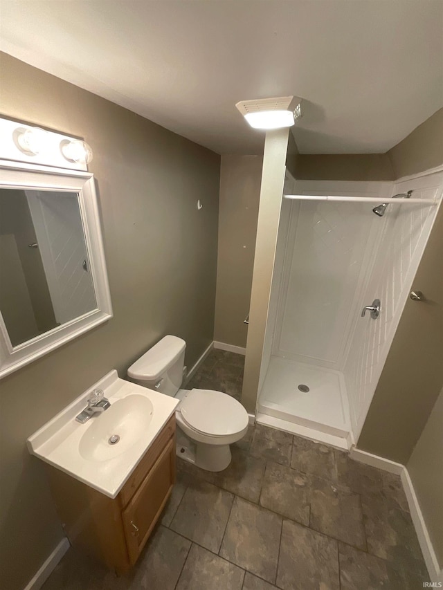 bathroom featuring toilet, a shower, and vanity