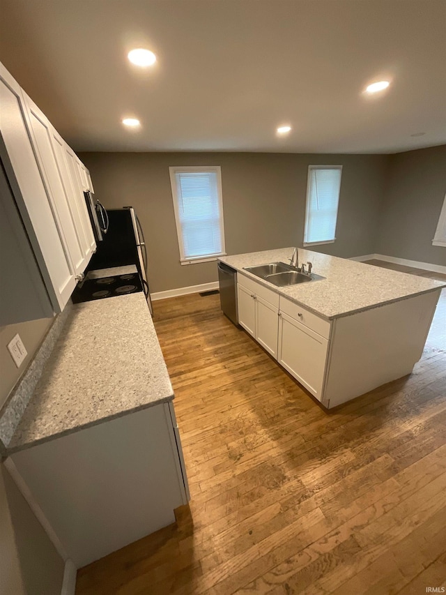 kitchen with white cabinets, sink, an island with sink, and light hardwood / wood-style flooring