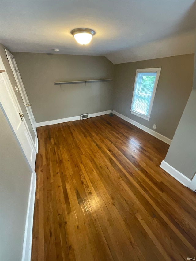 additional living space featuring dark wood-type flooring and vaulted ceiling