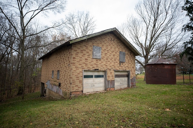 exterior space featuring a garage, a yard, and an outbuilding