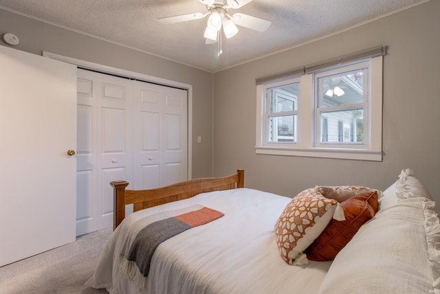 carpeted bedroom featuring ceiling fan, a textured ceiling, and a closet