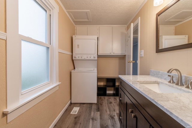 bathroom with vanity, hardwood / wood-style floors, a textured ceiling, and stacked washer and dryer