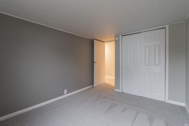 unfurnished bedroom featuring light carpet and a closet