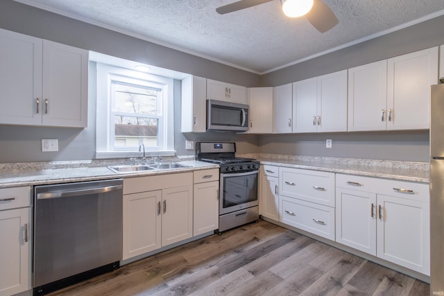 kitchen featuring crown molding, sink, light wood-type flooring, white cabinetry, and stainless steel appliances