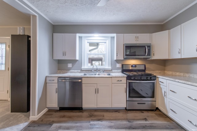 kitchen with white cabinets, stainless steel appliances, hardwood / wood-style flooring, and sink