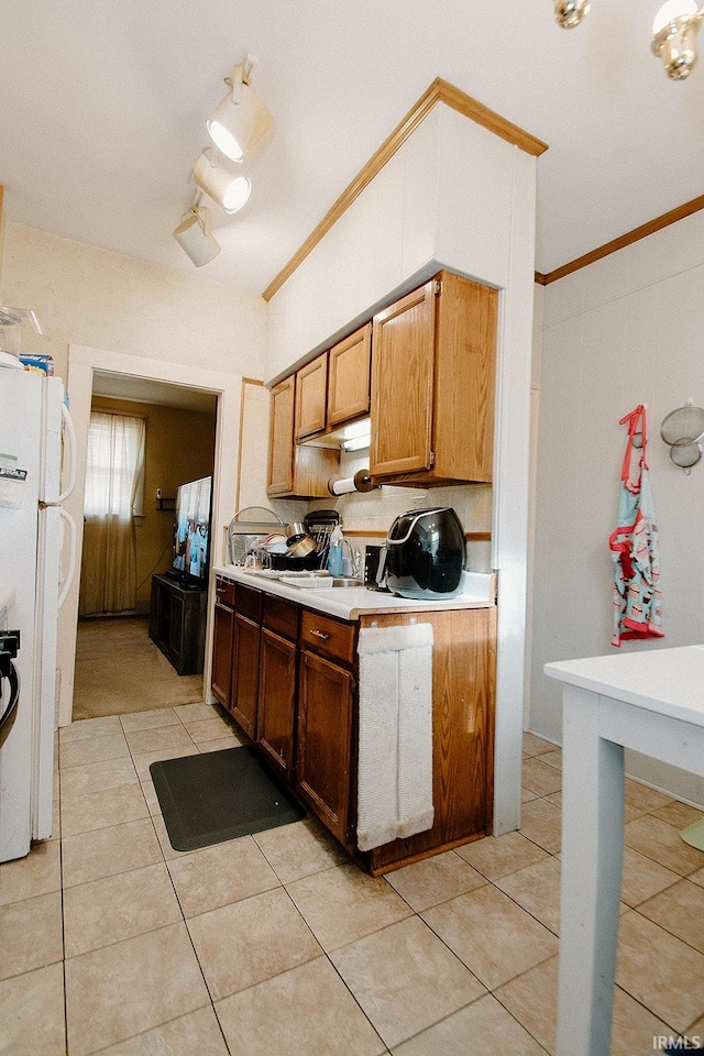 kitchen featuring crown molding, light tile patterned flooring, and white refrigerator