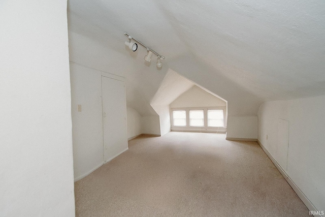 bonus room with a textured ceiling, light colored carpet, and vaulted ceiling